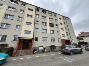 un grand bâtiment avec des voitures garées devant lui dans l'établissement Apartament COMFORT Centrum, à Krotoszyn