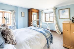 Cama en habitación con paredes y ventanas azules en Characterful Cottage in Heart of Dorset en Buckland Newton