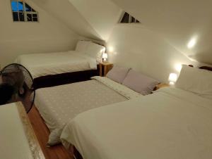 two beds in a small room with white sheets at Whyte Pyne Transient House in Baguio