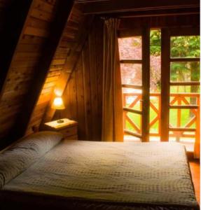 1 dormitorio con cama y ventana grande en Cabañas Mijos en El Bolsón
