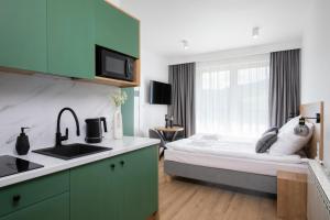 a bedroom with a bed and a kitchen with a sink at Villa Gorczański Zakątek Agroturystyka in Konina
