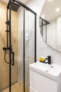 W łazience znajduje się biała umywalka i prysznic. w obiekcie Villa Gorczański Zakątek w mieście Konina