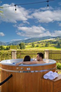 a man and a woman sitting in a hot tub at Villa Gorczański Zakątek in Konina