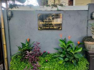 ein Schild an der Wand mit Pflanzen und Blumen in der Unterkunft Bukit Luah Sidemen in Sidemen