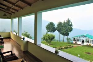 a living room with large windows with a view of a yard at Chirping Orchard, Mukteshwar in Mukteswar