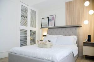 a bedroom with a white bed with a basket on it at Idahu Salt Lake Mesavirre Garden Residences Bacolod Modern Studio in Bacolod
