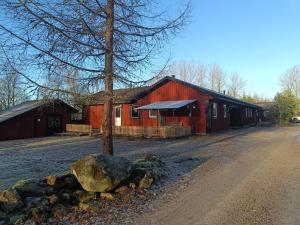 a red barn with a tree and a rock in front of it at Barts house in Länshult