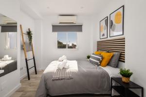 een slaapkamer met een groot bed met gele kussens bij Nordik Apartments Urban - Pedregalejo "Reine" in Málaga