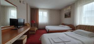a hotel room with two beds and a flat screen tv at Motel Monza in Blagoevgrad