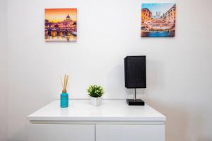a white desk with a speaker and three paintings at Jacuzzi Panoramica a Roma, Netflix e Comfort in Rome