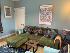 a living room with a green couch and a table at Elm Cottage in Alvescot