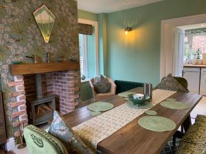 a dining room with a wooden table and a fireplace at Elm Cottage in Alvescot