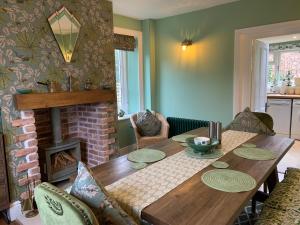 comedor con mesa de madera y chimenea en Elm Cottage en Alvescot