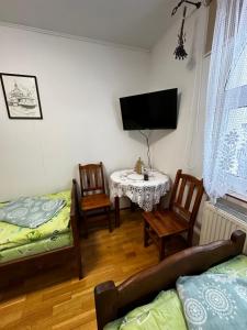 - un salon avec une table, des chaises et une télévision dans l'établissement Dom Pod Lipą, à Rymanów-Zdrój