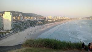 una spiaggia con una folla di persone e l'oceano di Suíte Studio 3 Enseada Tortuga Mobiliada a Guarujá