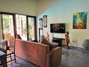 uma sala de estar com um sofá e uma televisão de ecrã plano em Villa Silence em Lovina