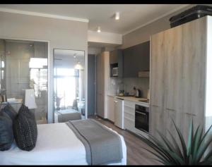 a bedroom with a white bed and a kitchen at The Trilogy,Menlyn Maine in Pretoria