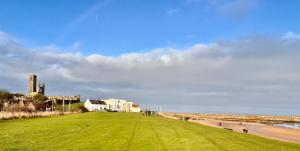 a grassy field next to a beach with people on it at No12 Bed and Breakfast, St Andrews in St. Andrews