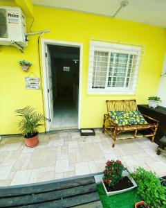 a yellow house with a bench on a patio at Pousada Ilha dos Corais in Palhoça