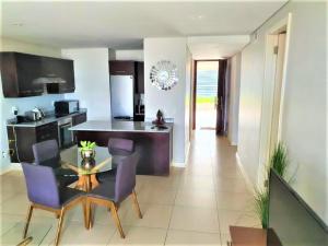 een keuken en eetkamer met een tafel en paarse stoelen bij Beacon Rock Apartment 208 in Durban