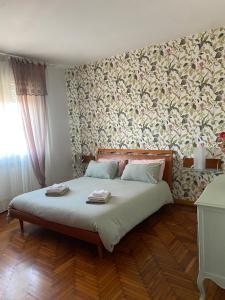 una camera da letto con un grande letto e carta da parati floreale di La porta accanto a Padova