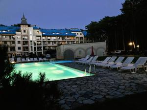 a swimming pool with chairs and a large building at Blue Mare BB in Łukęcin
