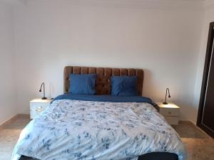 een slaapkamer met een bed met blauwe lakens en blauwe kussens bij Bel Horizon mosta in Mostaganem