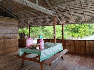 a table on a screened porch with a bench at Raja Ampat Diva homestay in Waisai