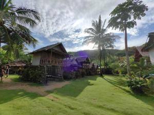 a group of houses with palm trees in a field at Ocam Ocam Casadyan Inn in New Busuanga