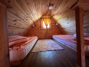 two beds in a wooden room with a window at Otantik Tas Ev in Dalaman