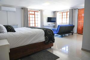 ein Schlafzimmer mit einem Bett und einem blauen Stuhl in der Unterkunft Green Lagoon Guest House Tawana in Gaborone