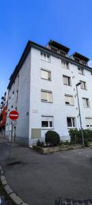 un grand bâtiment blanc avec un panneau rouge devant dans l'établissement Byt - apartmán - Robotnícka, à Bratislava