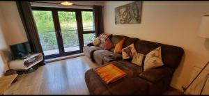 a living room with a brown couch with pillows at Brentwood Town Retreat - Large 2 bedroom apartment in Brentwood