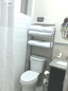 a bathroom with a toilet and a stack of towels at Suites Pineapple in Rock Sound
