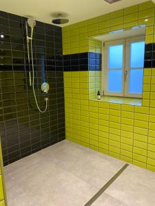 a bathroom with yellow and black tiles and a shower at Beim Has’n in Rimsting