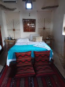 a bedroom with a bed with blue sheets and two pillows at مراقي سيوة Maraqi Siwa in Siwa