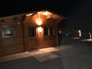 a wooden cabin with a door at night at Lochinvar - Highland Log Cabin with Private Hot Tub in Airdrie