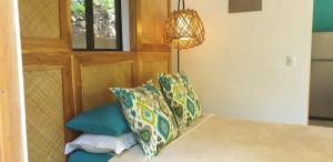 1 dormitorio con cama con almohadas y lámpara de araña en Casita Vinita, en Nosara