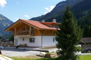 a house in the mountains with a tree at Ferienwohnung-Guem-2-Personen in Nesselwängle