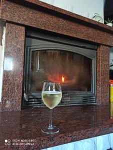 a glass of white wine in front of a fireplace at Mazurska Willa in Kretowiny