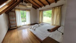 a bedroom with a large bed and large windows at Chacra Esaki in El Bolsón