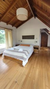 a bedroom with a large bed with a wooden floor at Chacra Esaki in El Bolsón