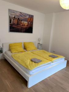 ein großes Bett mit gelber Bettwäsche und Kissen darauf in der Unterkunft Mondorf - klein aber fein zwischen Bonn & Köln in Niederkassel