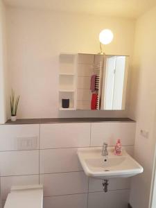ein weißes Badezimmer mit einem Waschbecken und einem Spiegel in der Unterkunft Mondorf - klein aber fein zwischen Bonn & Köln in Niederkassel