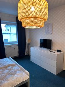 Schlafzimmer mit einem Bett, einem TV und einem Kronleuchter in der Unterkunft 4rooms - Bamberger Gemütlichkeit in Bamberg