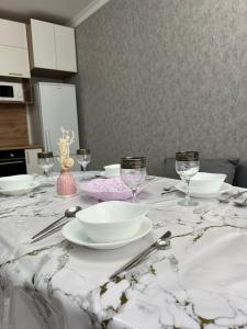 アスタナにある2х комнатная квартира Астана Левый берегの白いテーブル(皿、メガネ付)