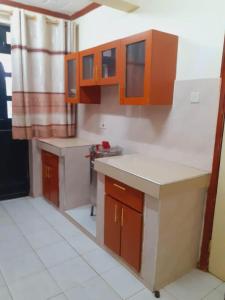 a kitchen with orange cabinets and white counter tops at Accommodation in Vihiga Bnb in Koiparak