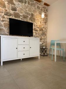 a white dresser with a tv on a stone wall at Violet in Vis