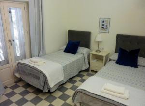 1 dormitorio con 2 camas y almohadas azules en APARTAMENTO APODACA en Cádiz