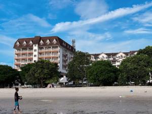 Ein Junge stand am Strand vor einem Hotel. in der Unterkunft Sunset view,Ground Floor to BEACH, 1-5pax in Port Dickson